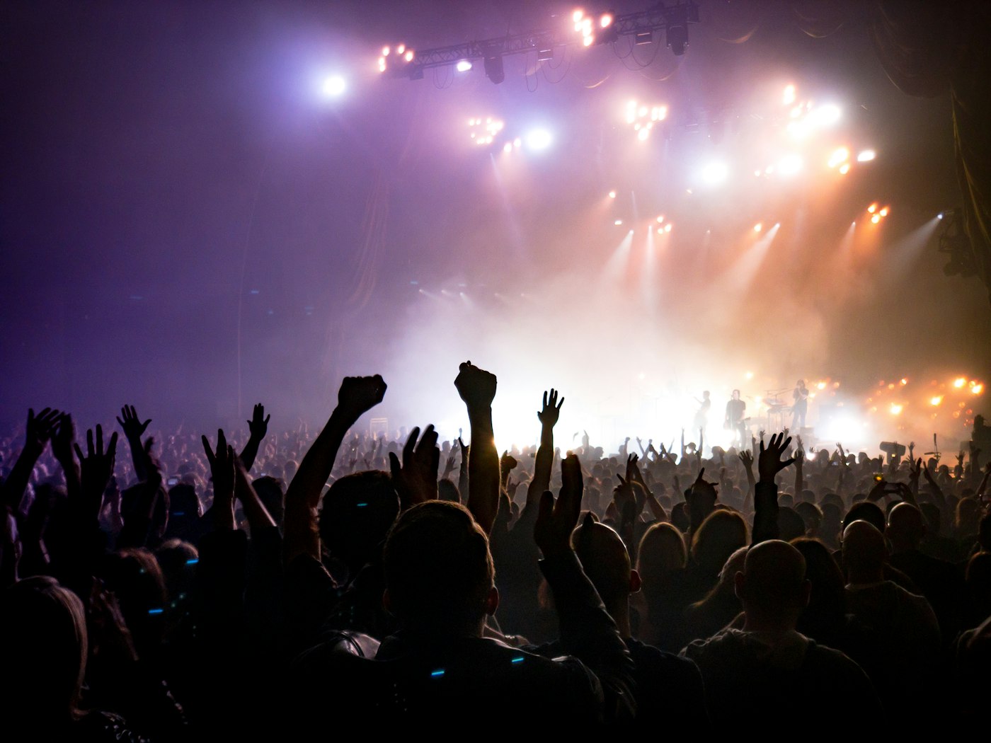 Crowd facing a lit stage in a dark venue
